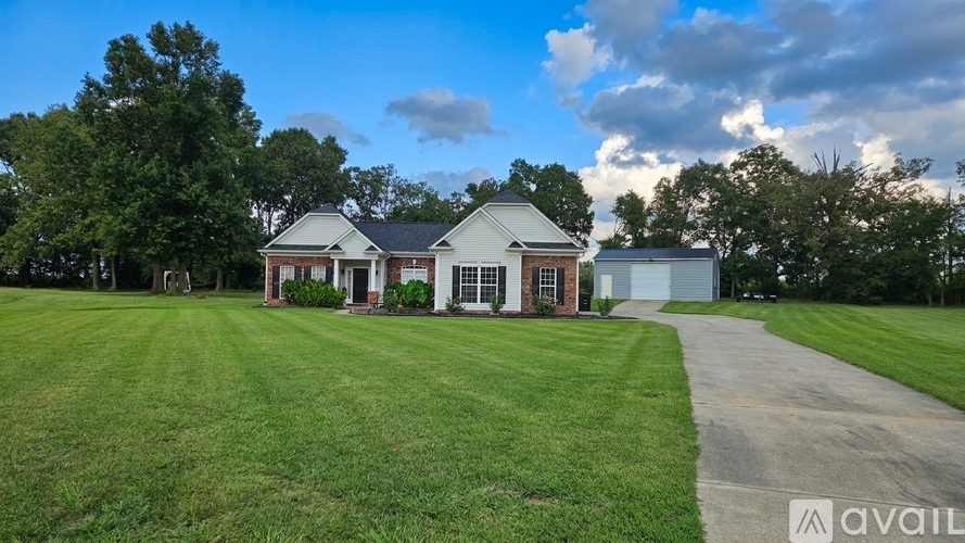 A house with a red door is surrounded by green grass and trees.
