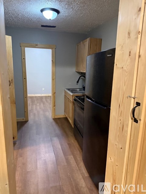 A kitchen with wooden cabinets and a black fridge.