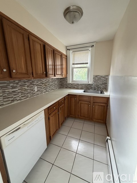 A kitchen with brown cabinets and a white dishwasher.