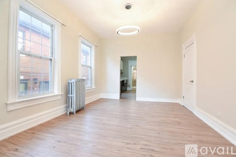 A spacious room with wooden floors and white walls.