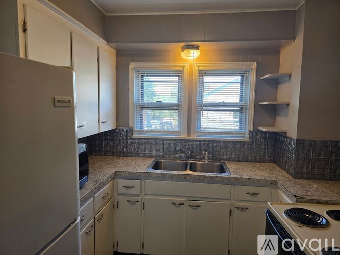A kitchen with a sink, stove, and cabinets.