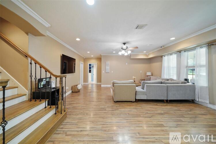 A spacious living room with a staircase on the left and a couch on the right.