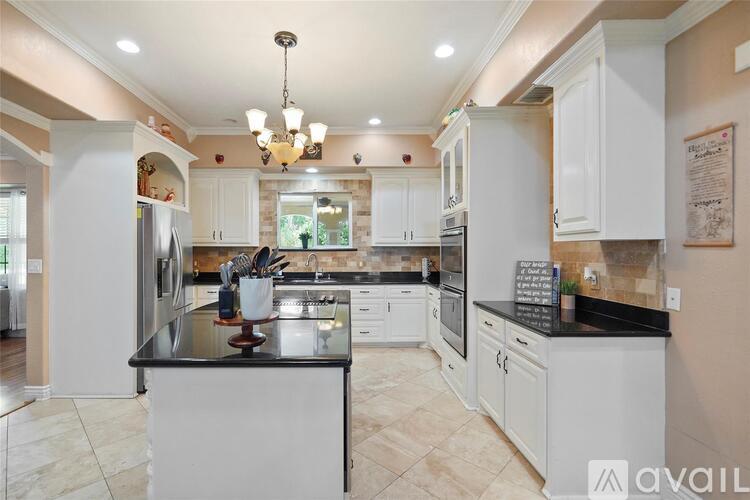 A kitchen with white cabinets and a black countertop.