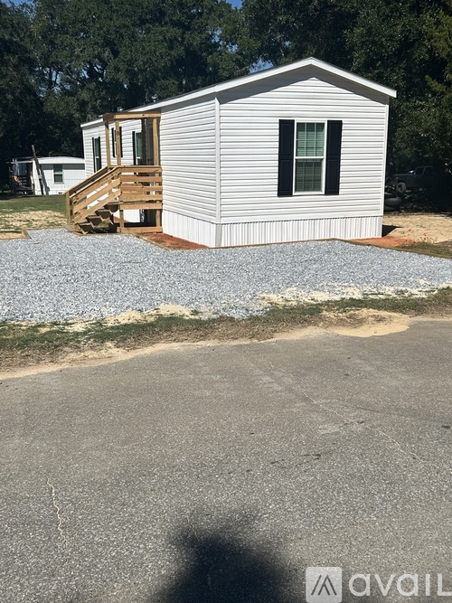 A mobile home with a deck and a gravel area in front.