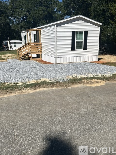 A mobile home with a deck and a gravel area in front.