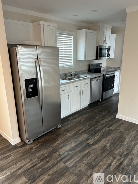 A kitchen with a refrigerator, microwave, and oven.