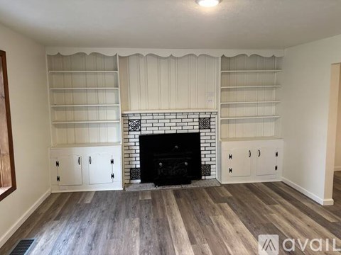 A living room with a fireplace and built-in shelves.