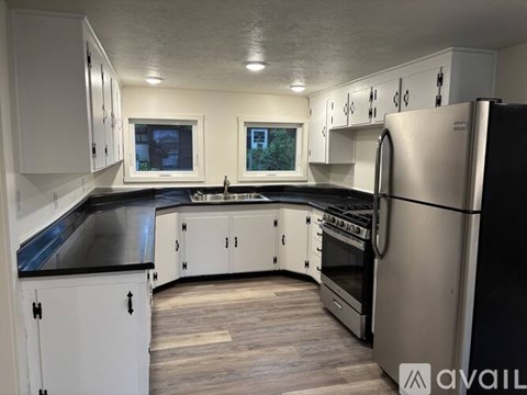 A kitchen with white cabinets and a black countertop.