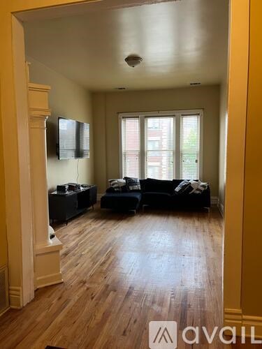 A living room with a black couch and a television on the wall.