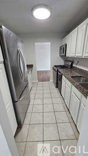 A kitchen with white cabinets and a tiled floor.