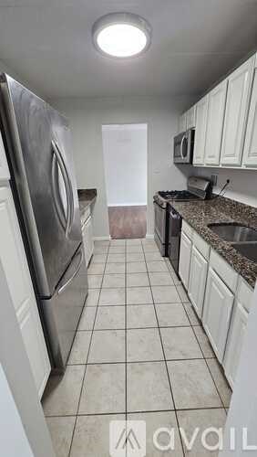 A kitchen with white cabinets and a tiled floor.