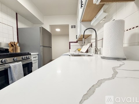 A kitchen with a white countertop and a stainless steel refrigerator.