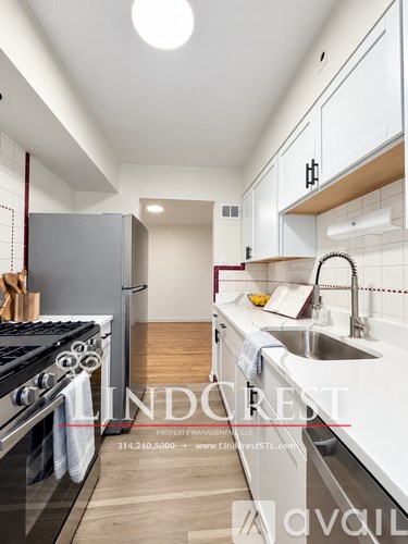 A modern kitchen with white cabinets and a stove top oven.