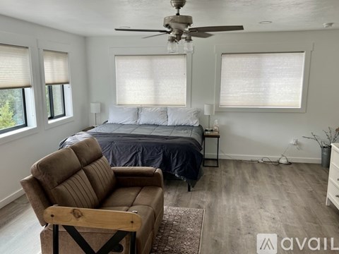 A bedroom with a bed, a chair, and a ceiling fan.