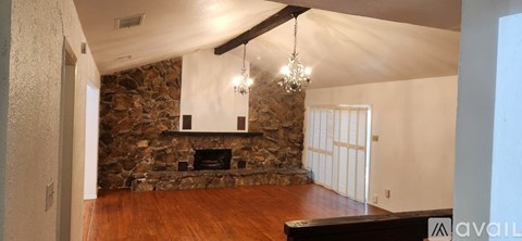 A living room with a stone fireplace and wood floors.