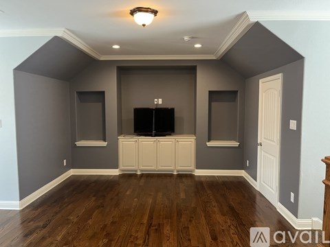 A living room with a television and built-in cabinets.