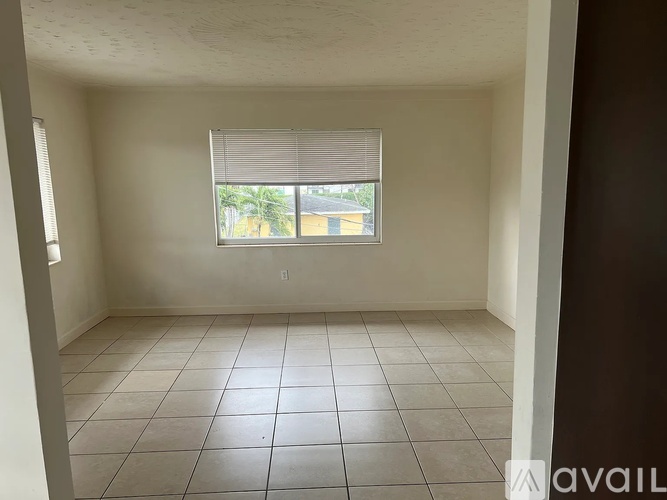 Empty room with tiled floor and a window with blinds.