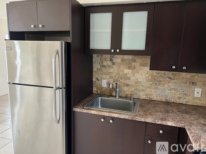 A kitchen with brown cabinets and a stainless steel refrigerator.