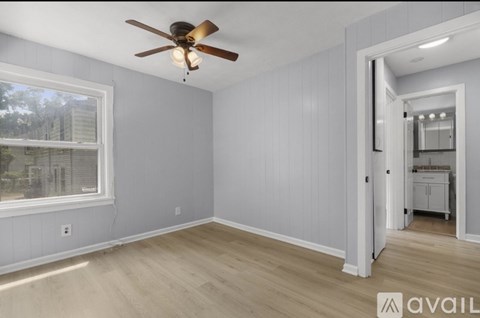 A room with a ceiling fan and a window overlooking a building.