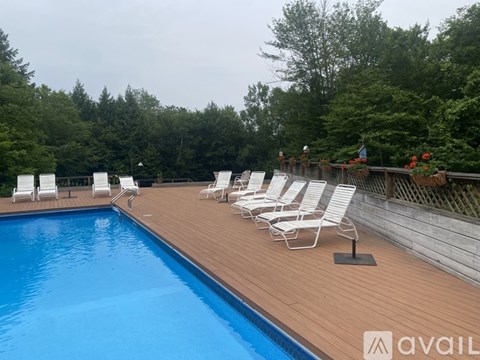 A pool with chairs around it and trees in the background.
