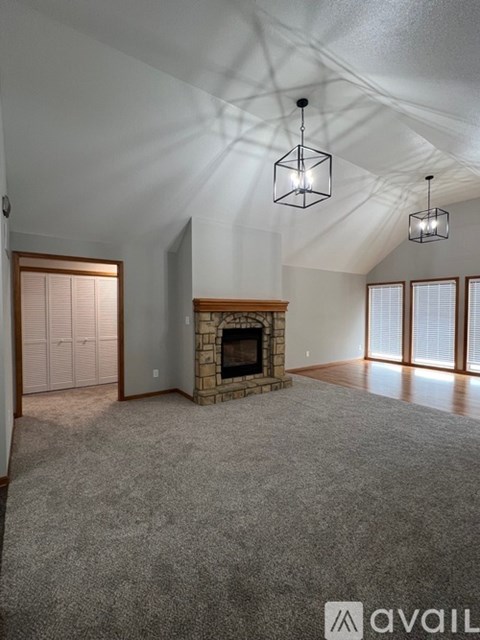A living room with a fireplace and a grey carpet.