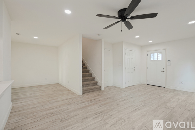 A spacious room with a staircase and a ceiling fan.