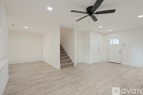 A spacious room with a staircase and a ceiling fan.