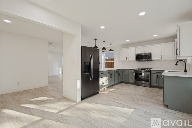 A modern kitchen with a black refrigerator and wooden flooring.