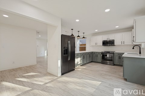 A modern kitchen with a black refrigerator and wooden flooring.
