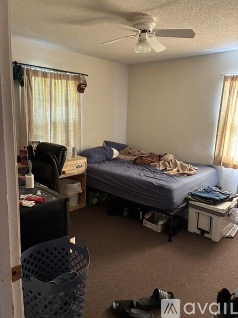 A bedroom with a bed, chair, and a fan.