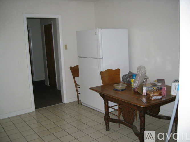 A kitchen with a white fridge, a table with chairs and a bowl on it.