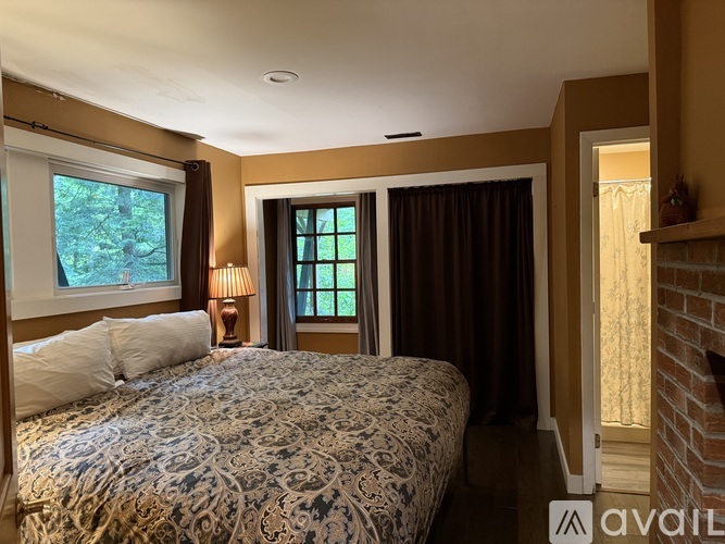 A bedroom with a large bed and a window with curtains.