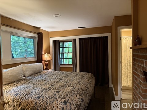 A bedroom with a large bed and a window with curtains.
