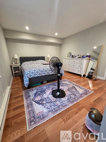 A bedroom with a bed, dresser, mirror, and rug.