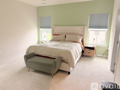 A bedroom with a large bed and a grey armchair.