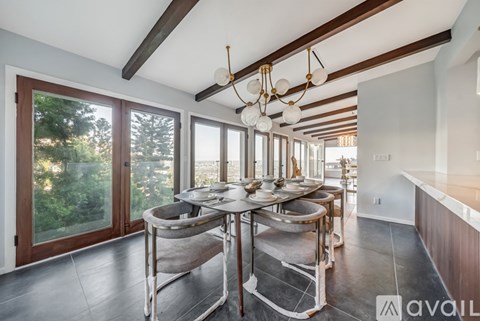 A kitchen with a table and chairs in front of a window with a view of trees.