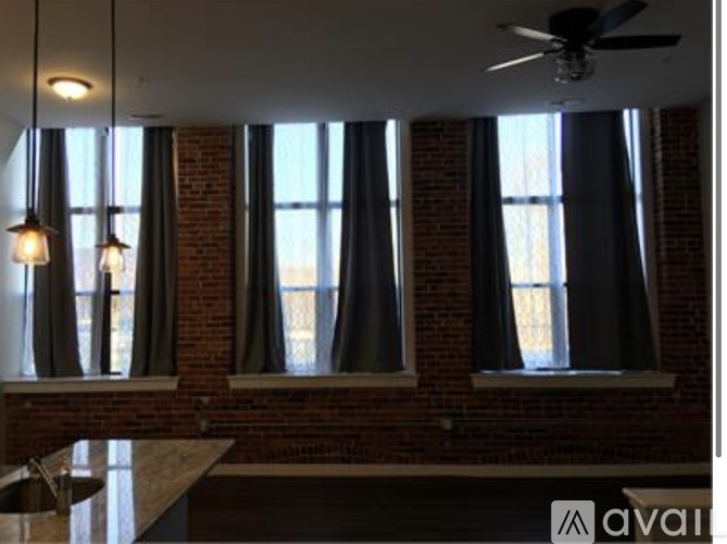 A kitchen with a brick wall and a ceiling fan.