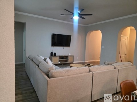 A living room with a large couch and a flat screen TV mounted on the wall.
