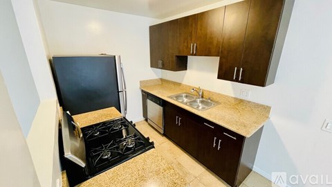 A kitchen with a black stove top and brown cabinets.