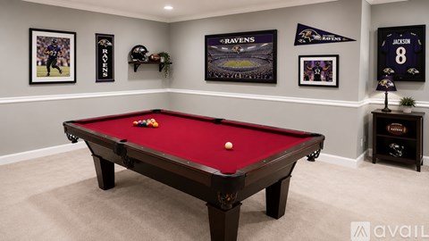A pool table in a room with a carpeted floor and walls decorated with Baltimore Ravens memorabilia.