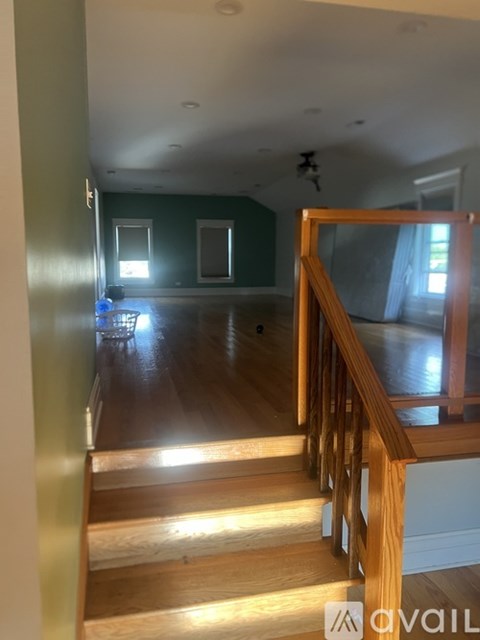 A wooden staircase leads to a room with a ceiling fan.