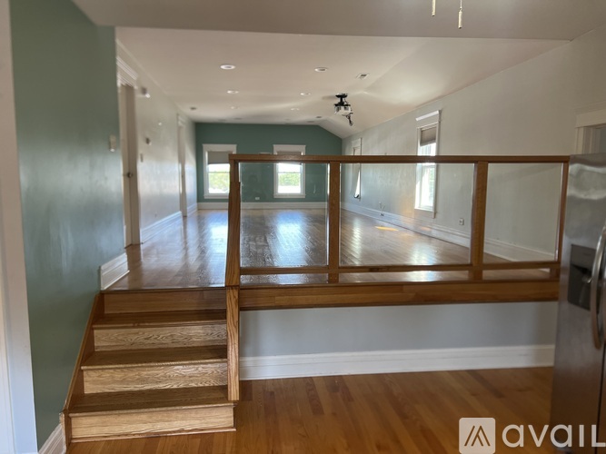 A long hallway with wooden stairs and a glass railing.