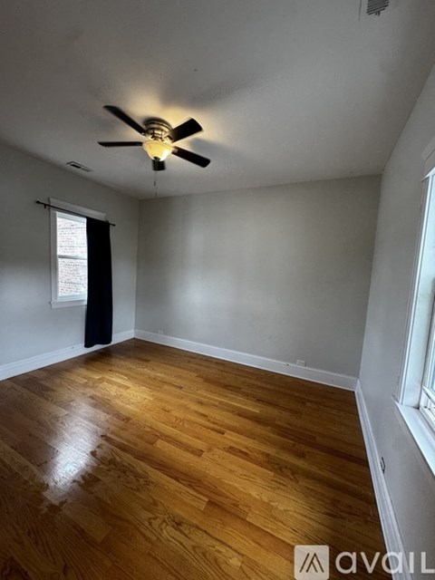 A room with wooden flooring and a ceiling fan.