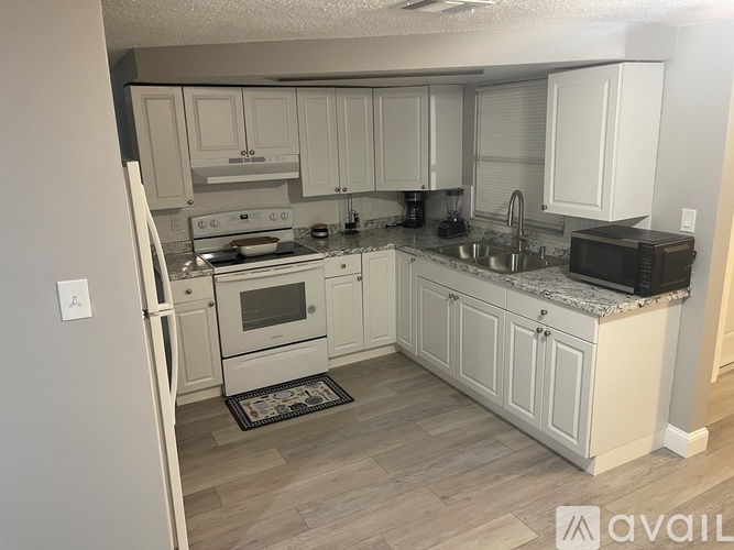 A kitchen with white cabinets and a refrigerator.