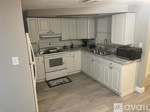 A kitchen with white cabinets and a refrigerator.