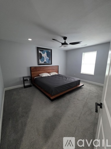 A bedroom with a bed, ceiling fan, and a picture on the wall.