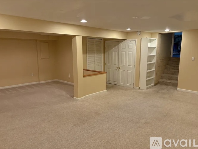 A spacious room with a staircase and a door leading to another room.