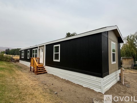 A black and white mobile home with a wooden staircase leading to the front door.