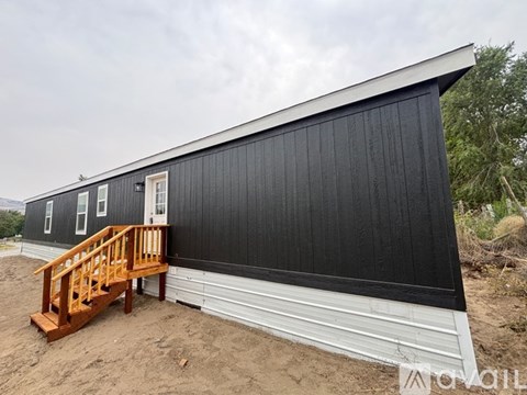 A black house with a wooden staircase leading to the door.