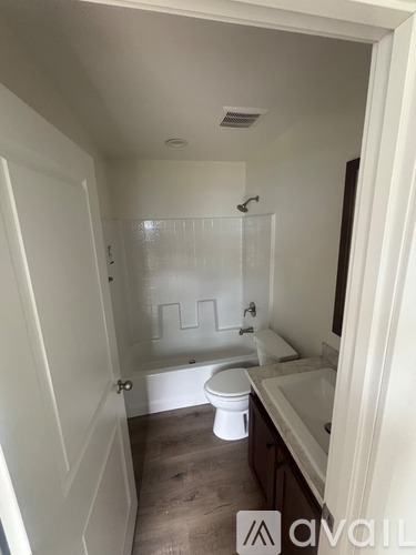 A small bathroom with a toilet, sink, and shower.